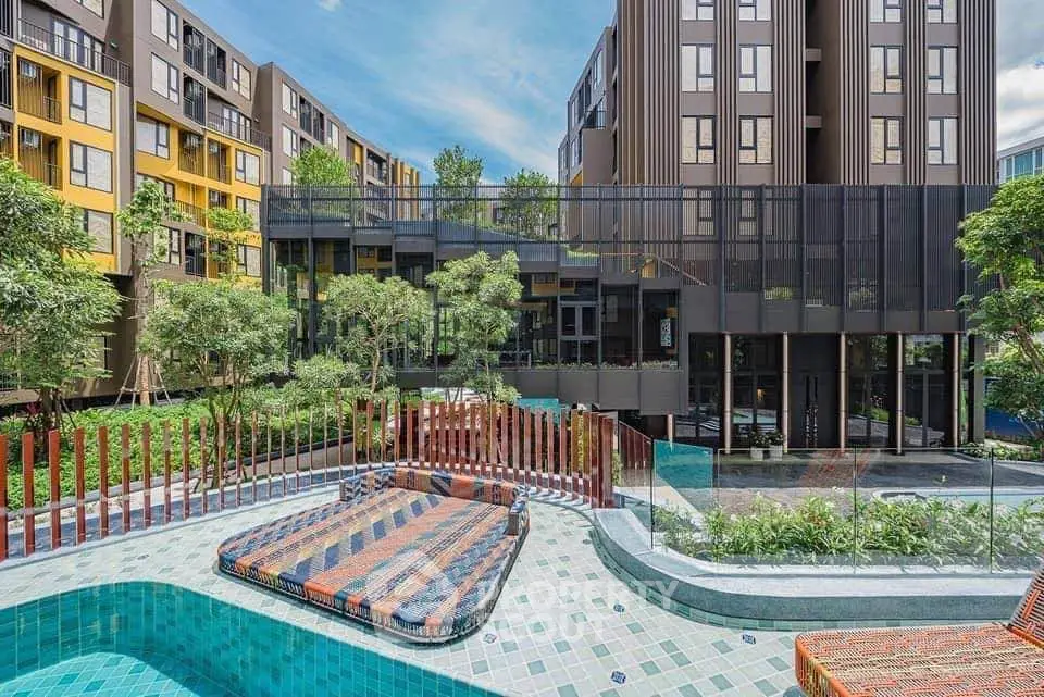 Modern apartment complex with pool and lush greenery, offering a serene urban living experience.