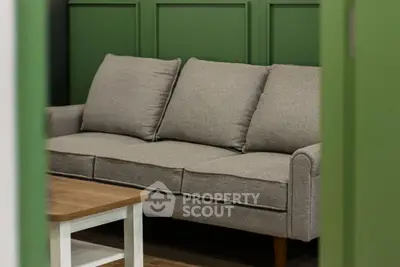 Cozy living room with stylish green paneling and comfortable gray sofa.