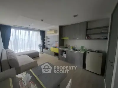 Modern open-plan living room with kitchenette and large window view.
