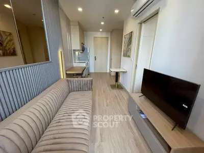 Modern living room with sleek design and neutral tones, featuring a plush sofa and flat-screen TV.