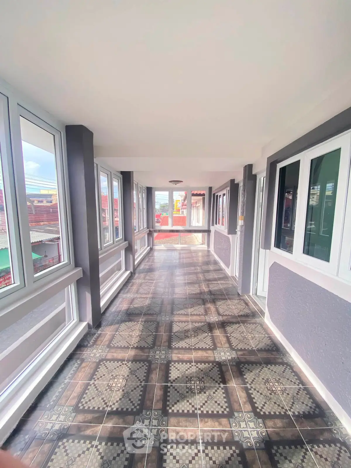 Bright corridor with large windows and patterned floor tiles in modern building.