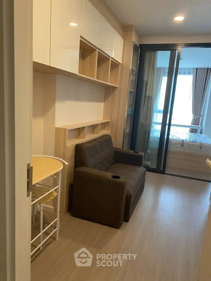 Cozy apartment interior with compact living area and bedroom view, featuring modern furnishings and ample natural light.