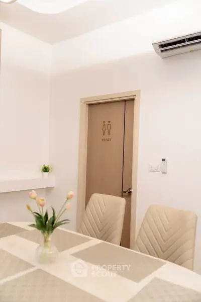 Modern dining area with elegant chairs and air conditioning, featuring a door leading to a restroom.