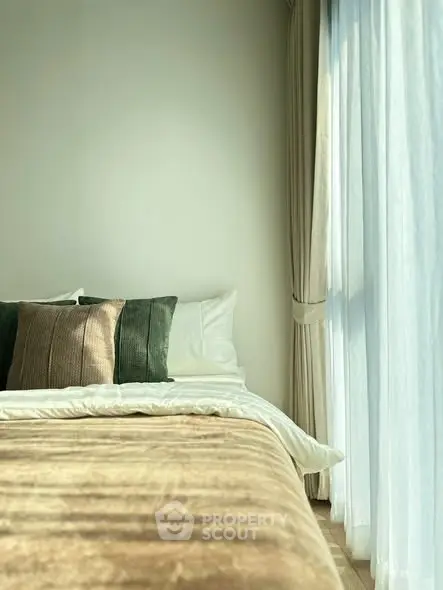 Cozy bedroom with elegant decor and natural light through sheer curtains.