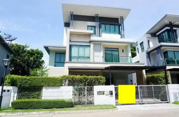 Modern three-story house with large windows and lush greenery