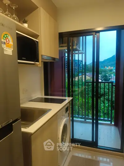Modern kitchen with balcony view, featuring sleek appliances and natural light.