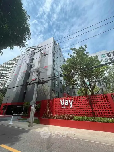 Modern apartment building with unique red facade and lush greenery