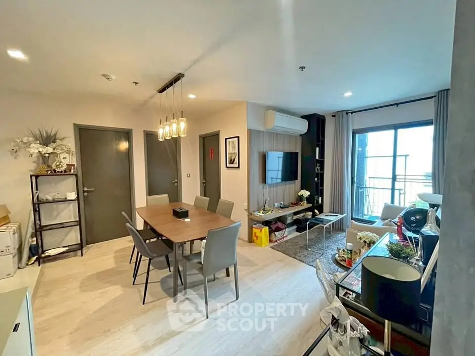 Modern living room with dining area and balcony access, featuring stylish decor and ample natural light.