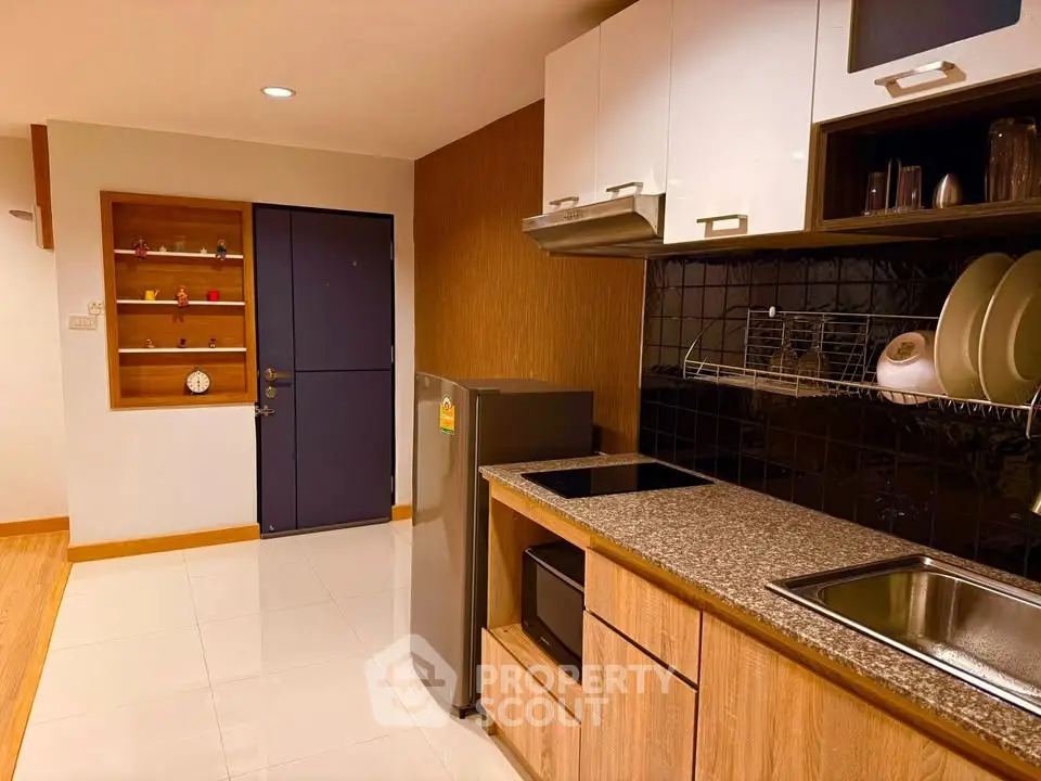 Modern kitchen with sleek cabinets and stainless steel appliances in a cozy apartment.