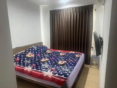 Cozy bedroom with wooden flooring and stylish curtains, featuring a mounted TV for modern living.
