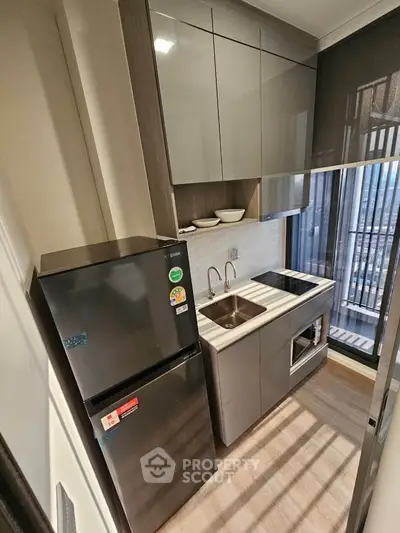 Modern compact kitchen with sleek cabinetry and appliances in a high-rise apartment.