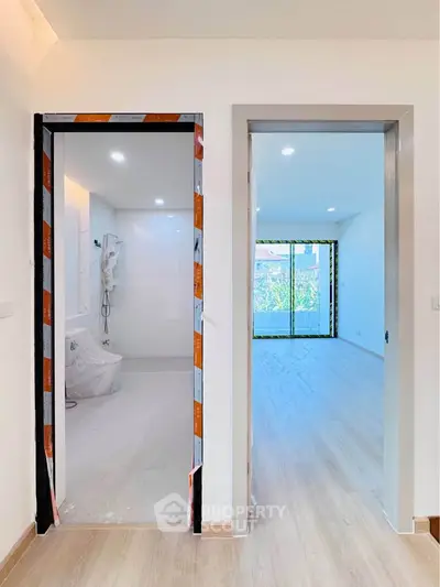 Modern apartment interior with bathroom and living room, featuring sleek design and natural light.