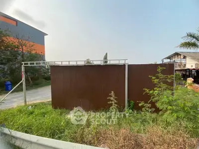 Vacant land with potential for development, surrounded by greenery and adjacent to a building.