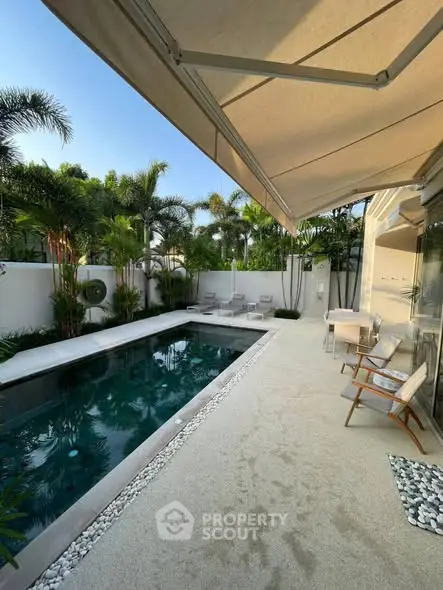Luxurious outdoor pool area with modern seating and lush greenery, perfect for relaxation and entertainment.
