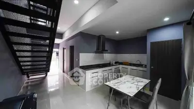 Modern kitchen with sleek design and open layout under a stylish staircase.