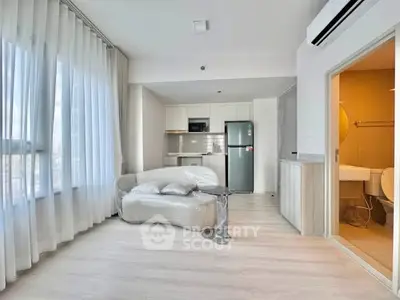 Modern open-plan living room with kitchen and bathroom, featuring sleek appliances and bright natural light.