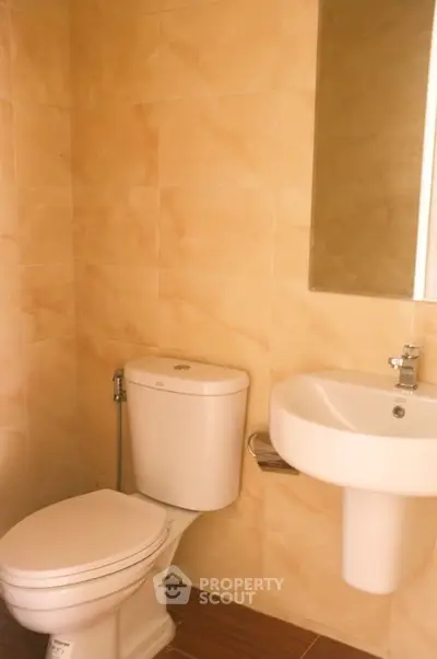 Modern bathroom with sleek fixtures and beige tile walls, perfect for a cozy home.