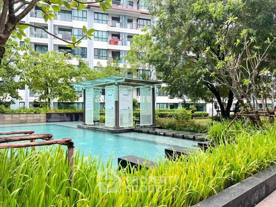 Luxurious residential building with serene pool and lush greenery, perfect for tranquil living.