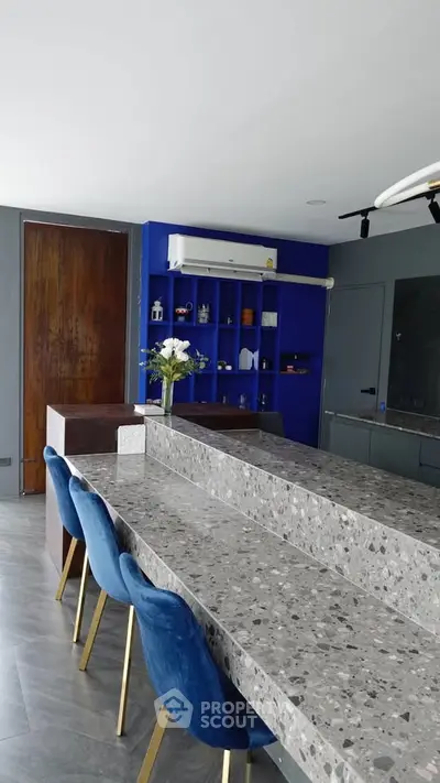 Modern kitchen with terrazzo countertops and blue accents, featuring sleek design and stylish bar seating.
