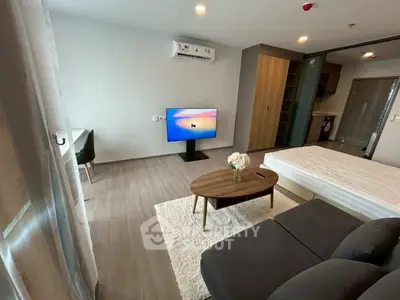 Modern studio apartment with sleek design, featuring a cozy living area, stylish furniture, and a wall-mounted TV.