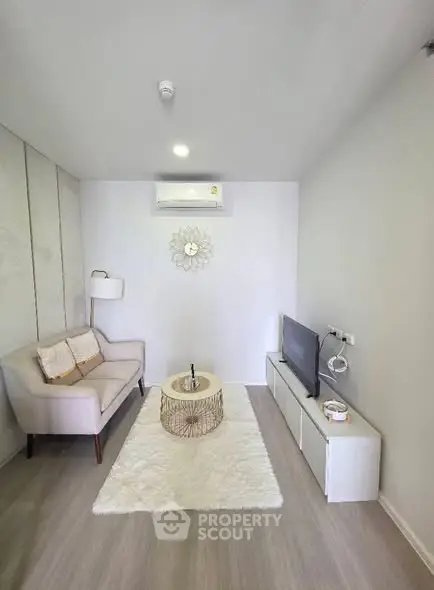 Modern living room with cozy sofa, stylish decor, and sleek TV setup in a bright, minimalist space.