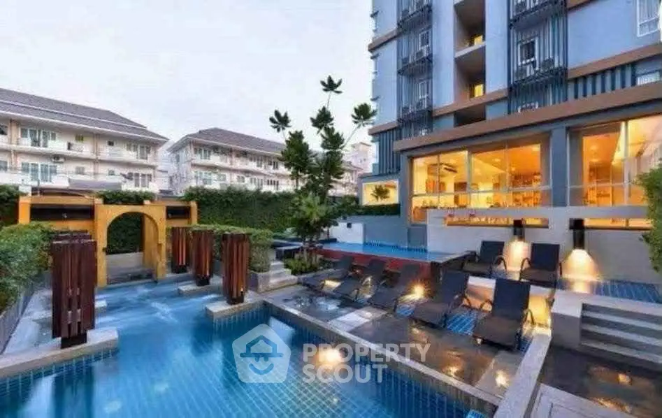 Luxurious apartment complex with modern pool and stylish outdoor seating area.