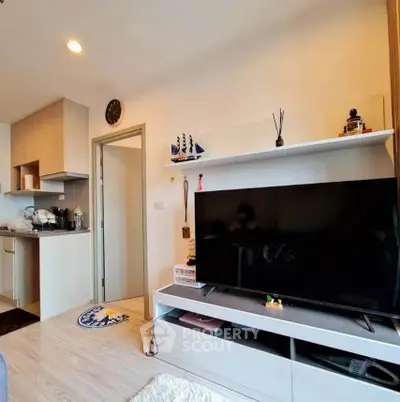 Modern living room with sleek TV setup and compact kitchen area, perfect for urban living.