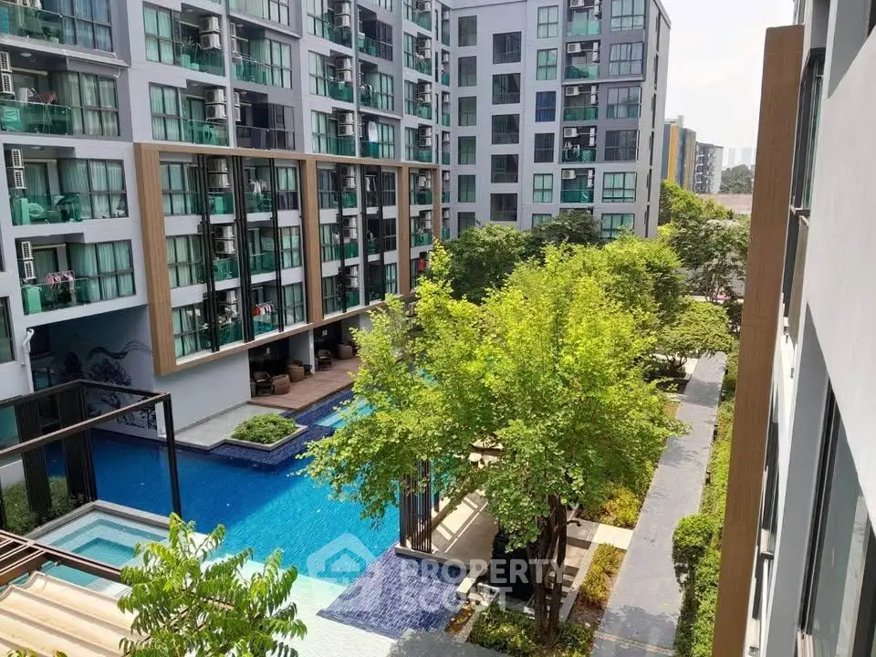 Modern apartment complex with pool and lush greenery, offering a serene urban living experience.