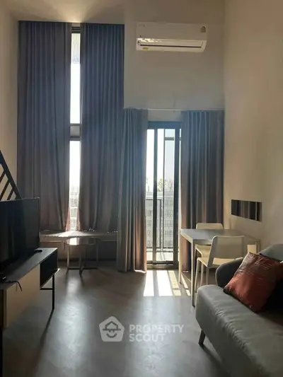 Modern living room with high ceilings, large windows, and stylish furniture in a contemporary apartment.