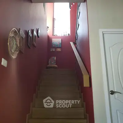 Charming staircase with red walls and decorative art pieces in a cozy home setting.