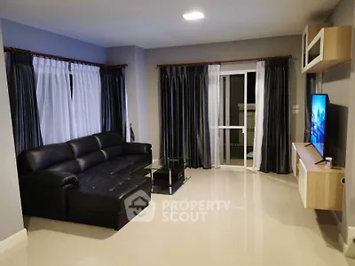 Spacious modern living room with sleek black leather sofa and large windows for natural light.