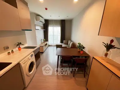 Modern open-plan living room with kitchen, featuring washing machine and stylish decor.
