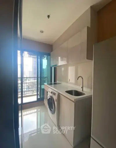 Modern kitchen with washing machine and city view from balcony.