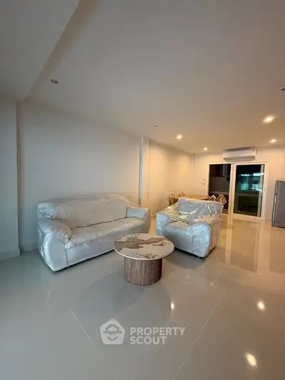Spacious modern living room with sleek furniture and glossy tiled floors, perfect for contemporary living.