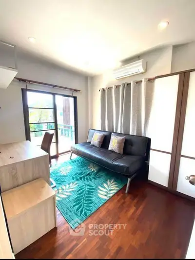 Bright living room with modern decor and balcony access, featuring a stylish sofa and wooden flooring.