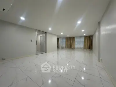 Spacious modern living room with marble flooring and large windows for natural light.
