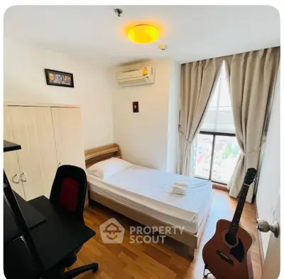 Cozy bedroom with wooden flooring, single bed, and guitar by the window.