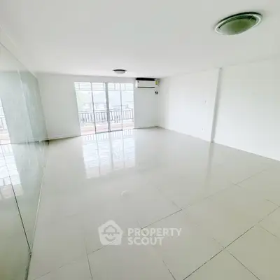 Spacious empty living room with large windows and balcony access