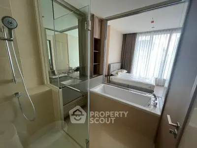 Modern bathroom with glass shower and bathtub adjacent to a bedroom with natural light.