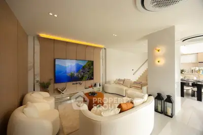 Luxurious modern living room with elegant furniture and large TV, open layout to dining area.
