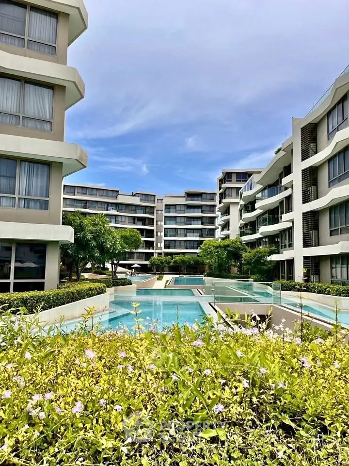 Luxurious residential complex with modern architecture and inviting swimming pool under a clear blue sky.