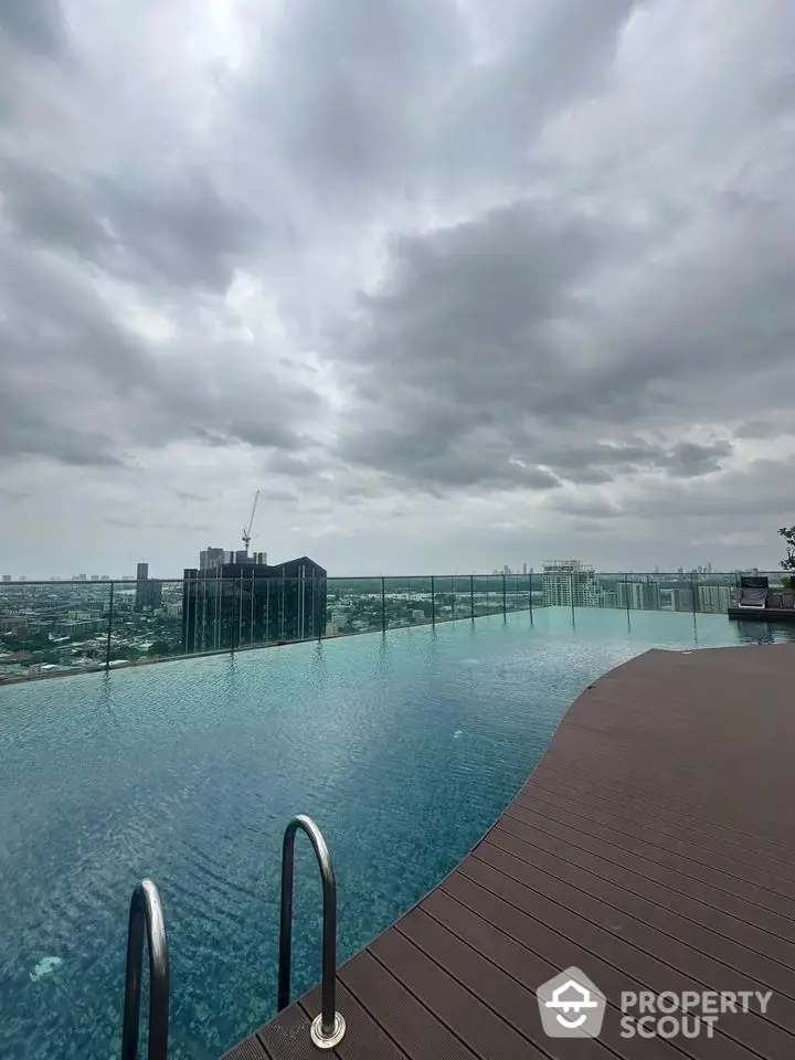 Luxurious rooftop infinity pool with stunning city skyline view under cloudy skies.