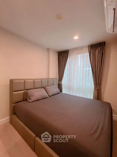 Cozy bedroom with modern decor and large window with curtains, perfect for relaxation.