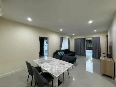 Spacious modern living room with elegant marble dining table and cozy seating area.