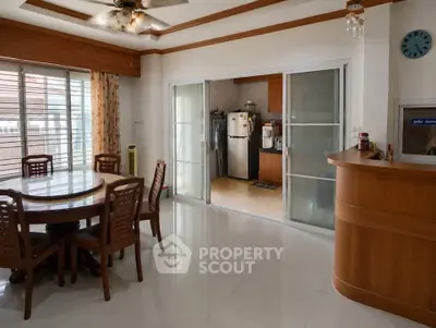 Spacious dining area with wooden furniture and sliding doors leading to a modern kitchen.