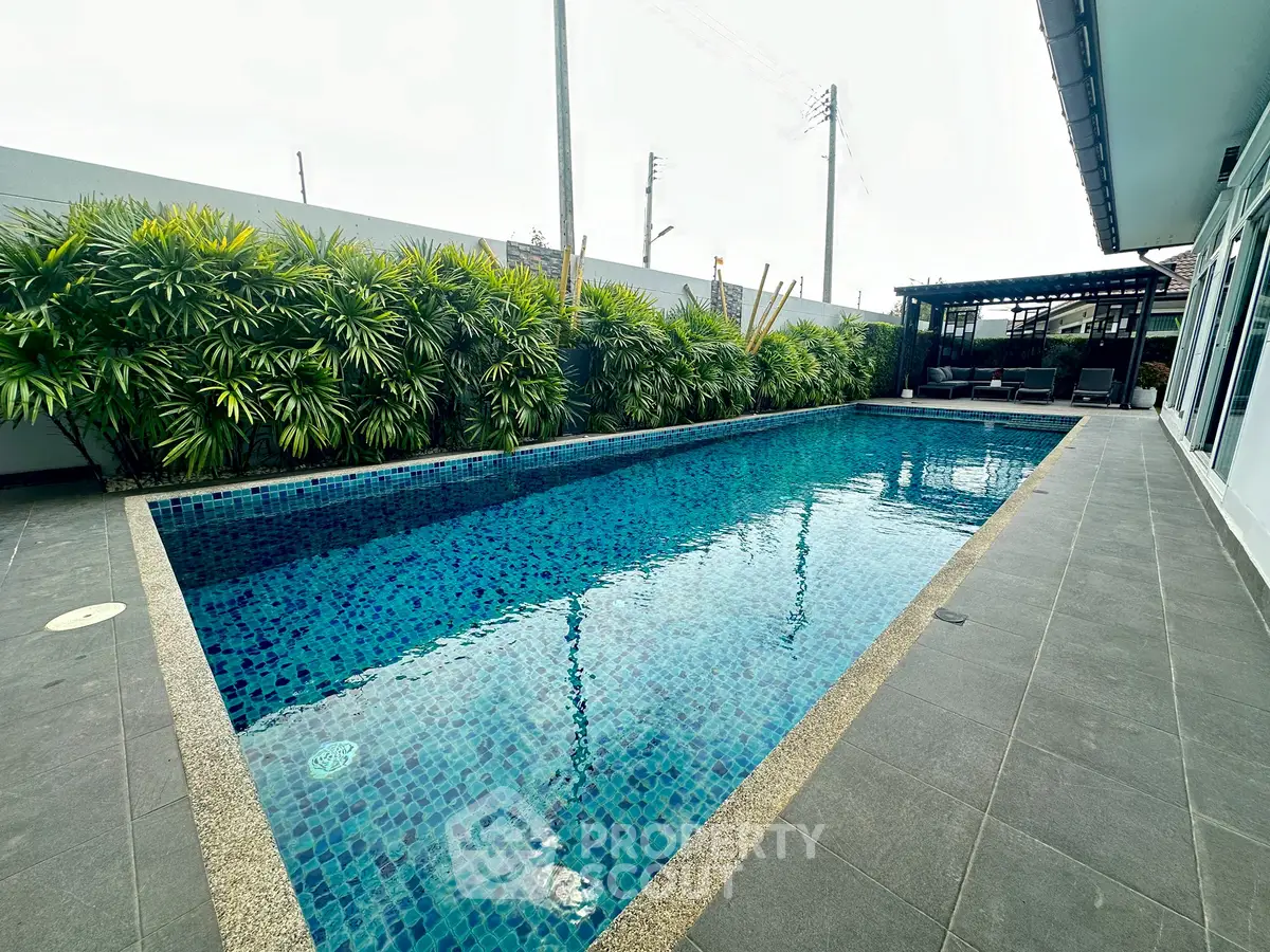 Luxurious private pool with lush greenery and modern patio area, perfect for relaxation.