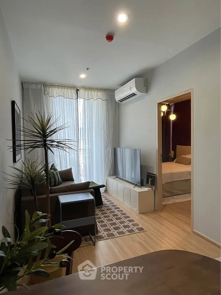 Modern living room with sleek furniture and natural light, adjacent to a cozy bedroom.