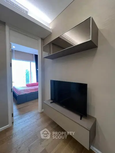 Modern apartment interior with sleek TV setup and view into stylish bedroom