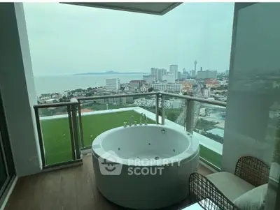 Luxurious balcony with jacuzzi offering stunning ocean and city views in high-rise apartment.