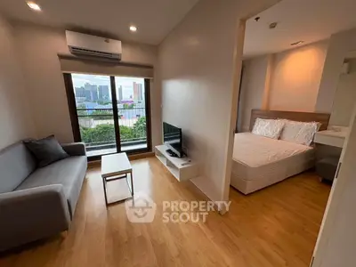Modern apartment with cozy living room and bedroom, featuring a city view from the window.